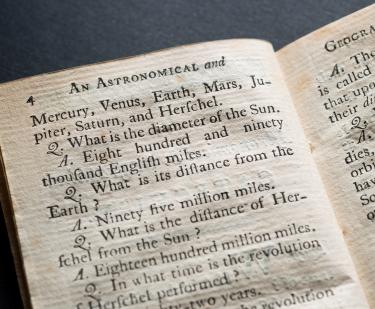 Detail from a printed text shows questions and follow-up answers about astronomy.