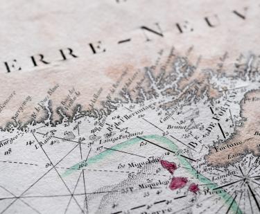 Detail of a hand colored printed map shows text in French reading "Terre-Neuve," latitude and longitude lines, and labels over other geographical areas.