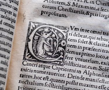 Detail of a printed books shows text in Latin and decorative typography.