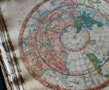 Detail from a colored manuscript map shows the world labeled with text in Latin.