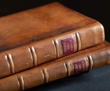 Detail of two books shows brown leather binding and spine labels "1" and "2" and the shortened title.