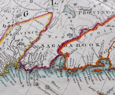 Detail of a colored, engraved map shows pink, orange, and yellow used to outline areas and labels in English such as "Penobscots."