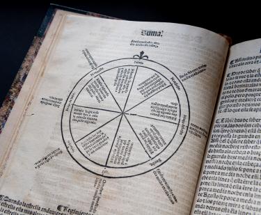 Detail of a printed book shows a circular illustration and text in Spanish.
