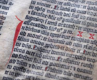 Detail of a leaf of the Gutenberg bible printed in black and red ink shows Latin text.