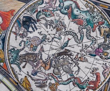 Detail from an engraved, hand colored map shows vivid illustrations of celestial sphere with their constellations and zodiac signs around the sun. Labels in Dutch read "Taurus," "Orion," and "Saittarius."