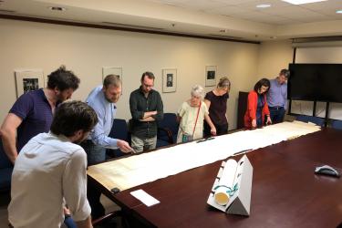 group of people standing around a map measuring over 14 feet long