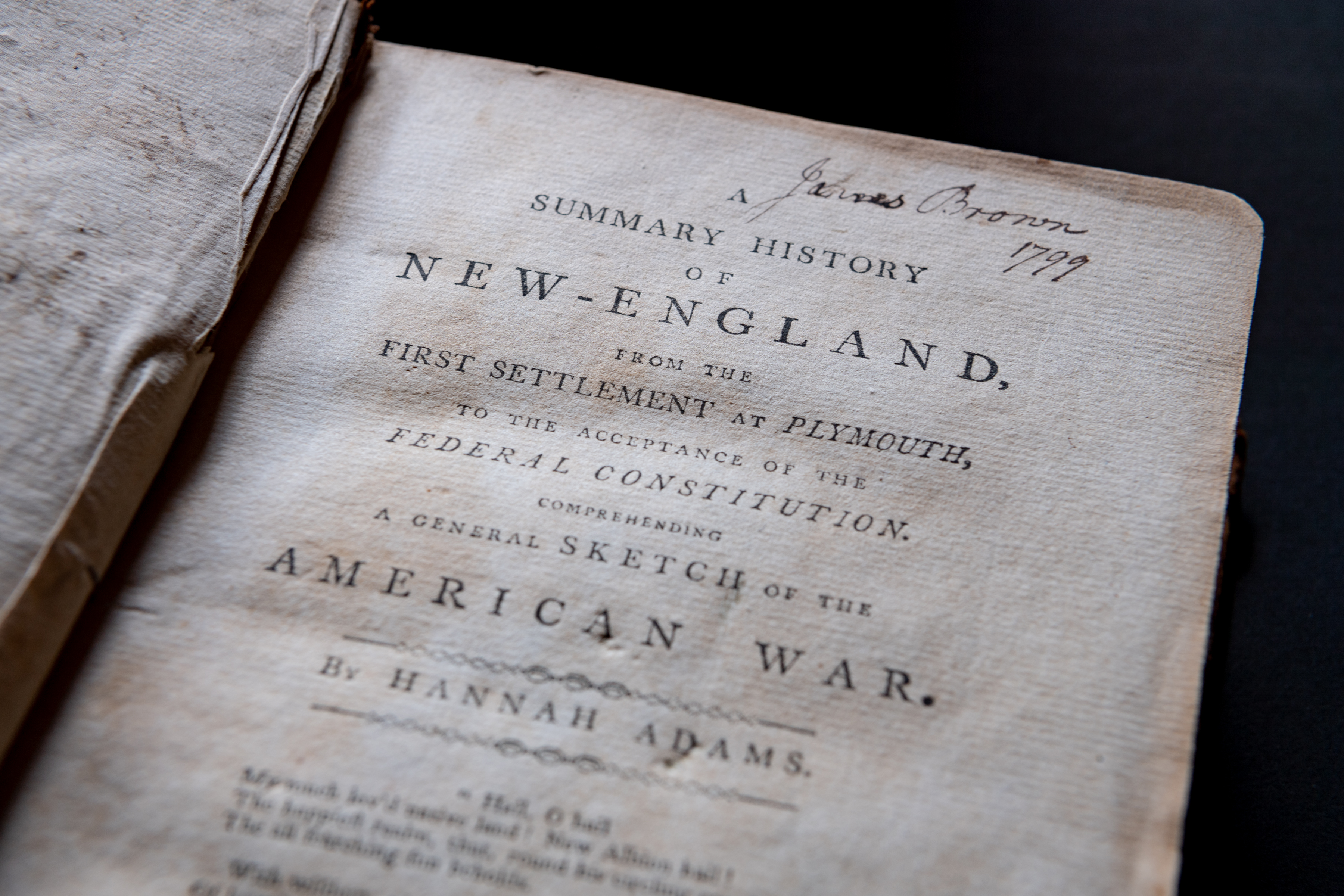 Detail of a printed book shows title page with manuscript notations at the top of the page.