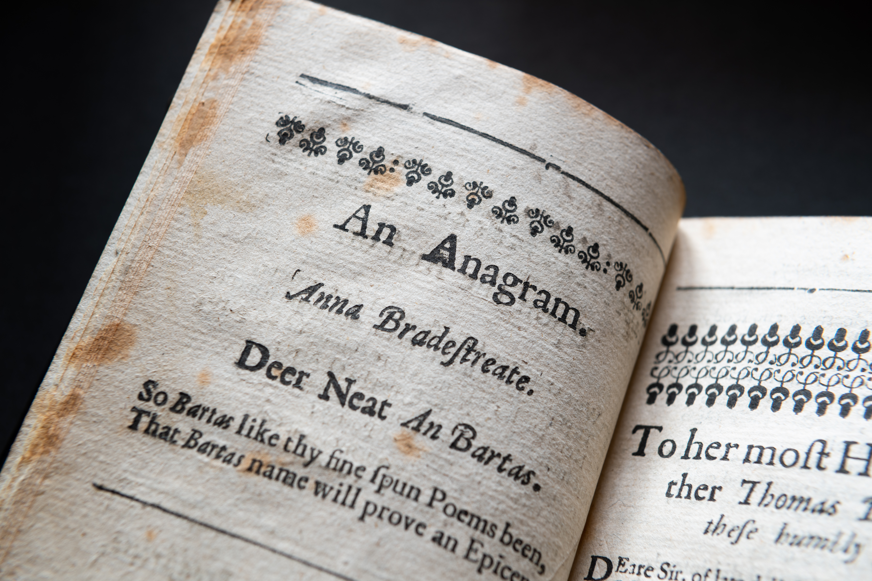 Detail of a printed book shows worn papers and header text reading "An Anagram. Anna Bradestreate" and other text in English.