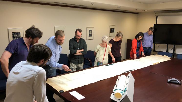 group of people standing around a map measuring over 14 feet long