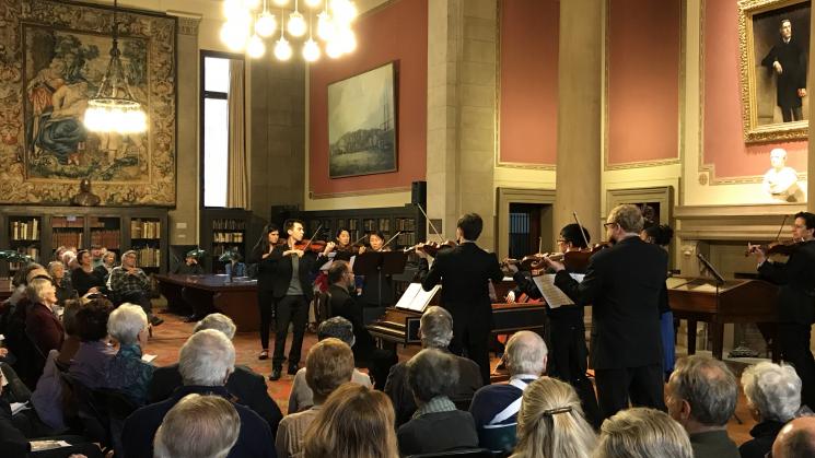 Group of people seated in the John Carter Brown Library reading room, listening to live performance by Community MusicWorks.