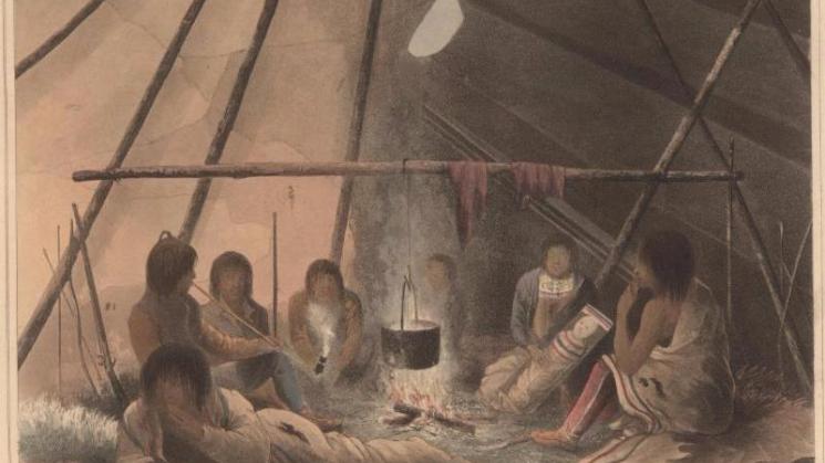 group of indigenous people sitting around a fire in an enclosed space