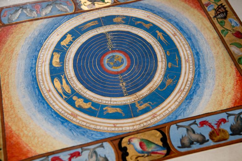 Detail of a colored manuscript map shows cosmographical view of the world and zodiac. Inks in red, green, and blue and gilded details are used throughout the map and decorative border.