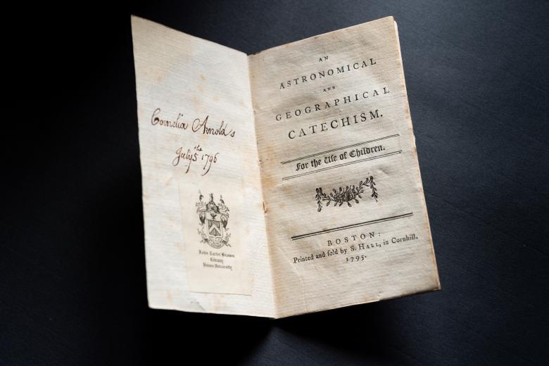 Detail from a printed title page shows manuscript handwriting on the left and "An Astronomical and Geographical Catechism for the Use of Children" on the right.