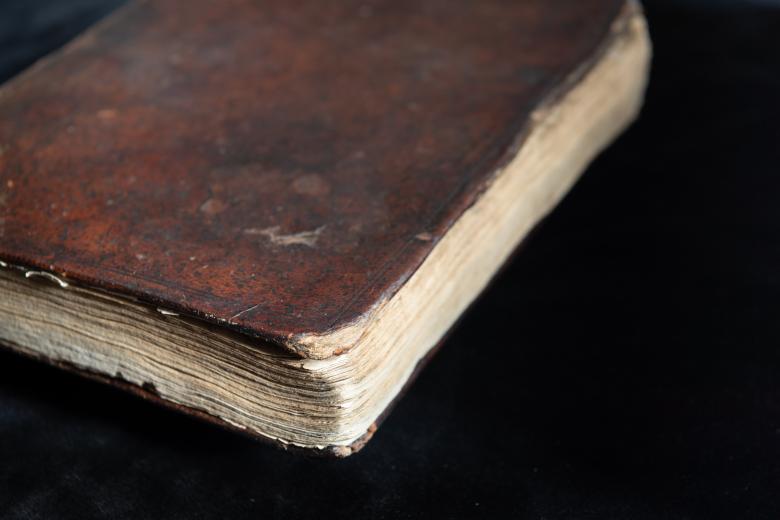 Detail of leather book binding shows wear on the lower right corner.