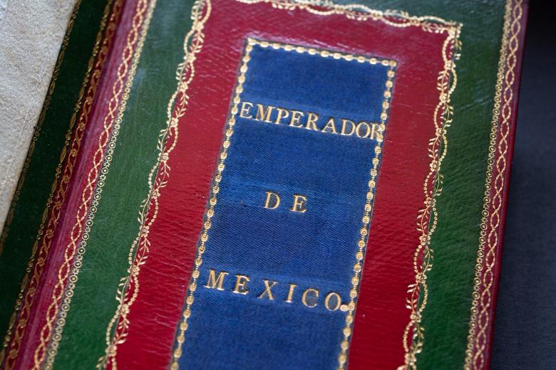 Printed book bound in red and green Morocco and blue silk with text in Spanish reading "emperador de Mexico" on the inner back cover.