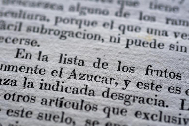 Detail of a printed book shows text in Spanish reading "en la lista de los frutos."