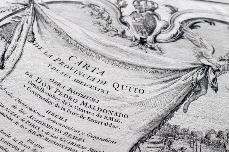 Detail of a printed map shows decorative cartouche includes angels and text in Spanish that indicates the map's title.