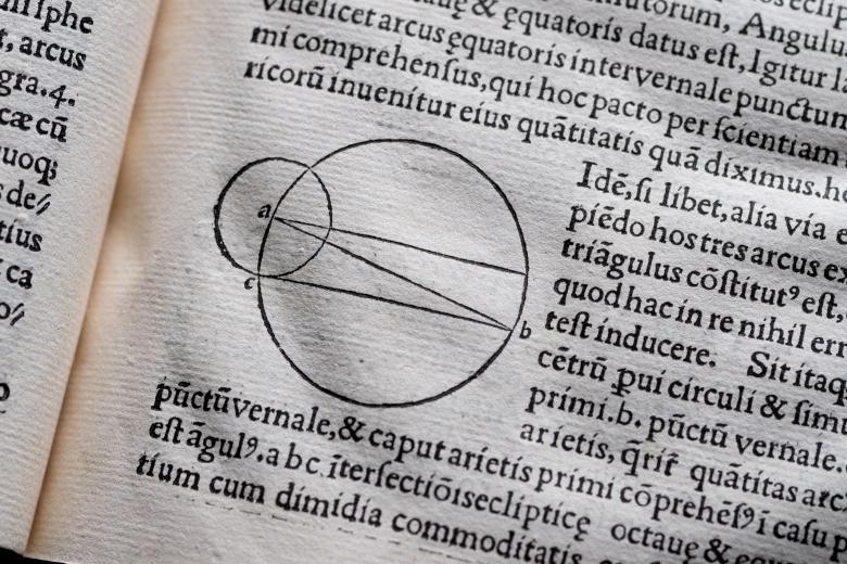 Detail of a printed books shows text in Latin and geometric diagram including two circles.