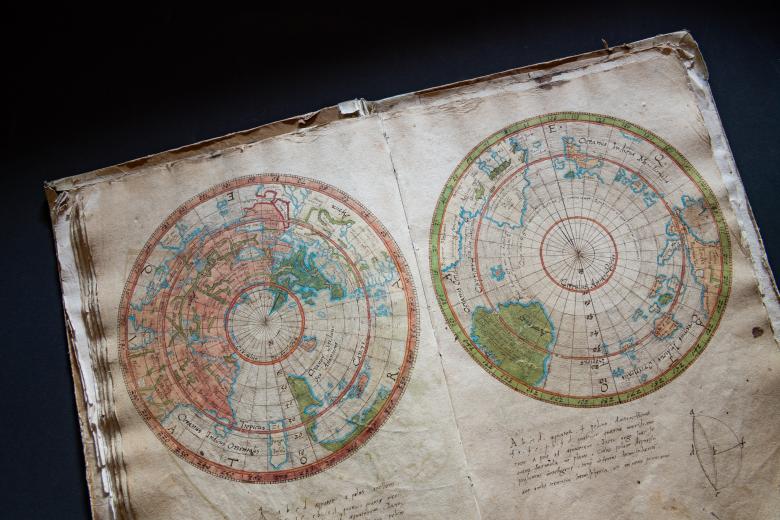 Detail from a colored manuscript map shows the world split in two circles representing the two hemispheres. Manuscript annotations in Latin are also visible.