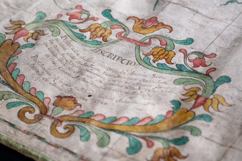 Detail of a colored manuscript map shows decorative cartouche with text in Spanish reading "Descripcion" at the top.