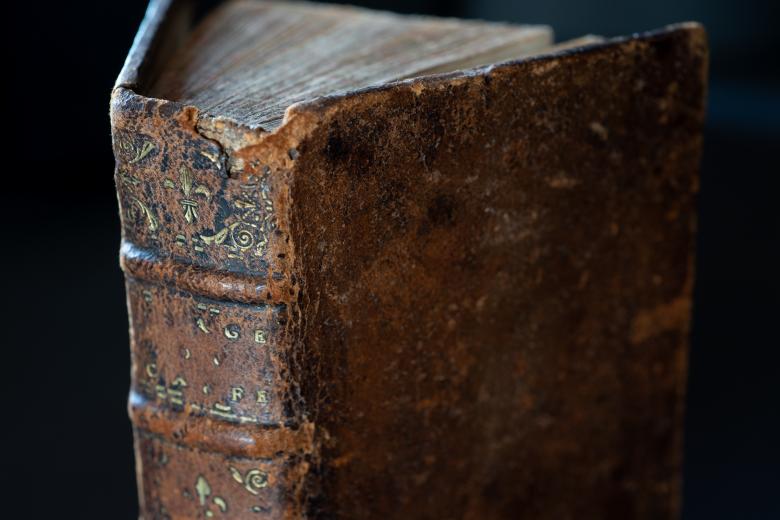 Detail of a brown leather book cover shows some faded black and gold detail.