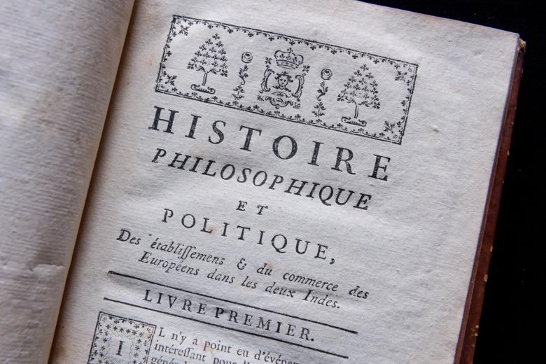 Detail of a printed book shows a decorative headpiece and text in French reading "Livre Premier."