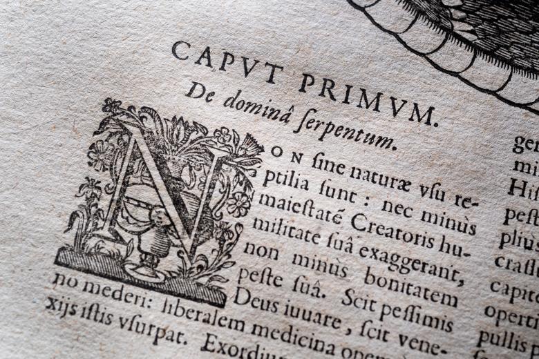 Printed text shows Latin text with a decorated letter at the top of the page.