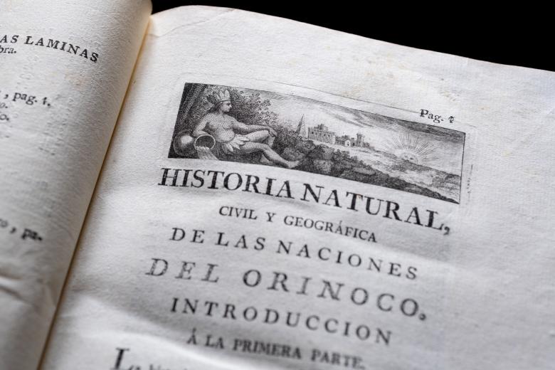 Detail of a printed book shows a decorative head piece on the title page written in Spanish.