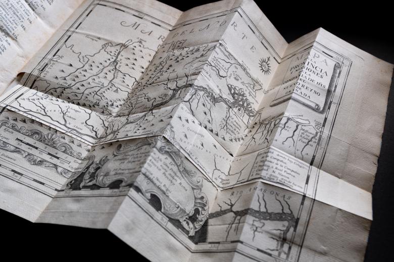 Detail of a printed fold-out map shows text and labels in Spanish and topographical information. Scale and cartouche are also included at the bottom of the page.