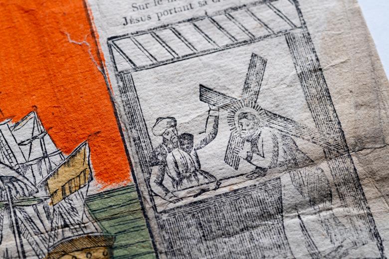 A detail of a woodcut image where Jesus carries the cross as a man stands nearby. Part of a ship is partly visible.