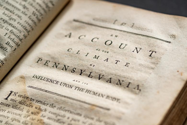 Detail of a printed book shows text in English reading "An account of the climate of Pennsylvania" on the first half of the page.