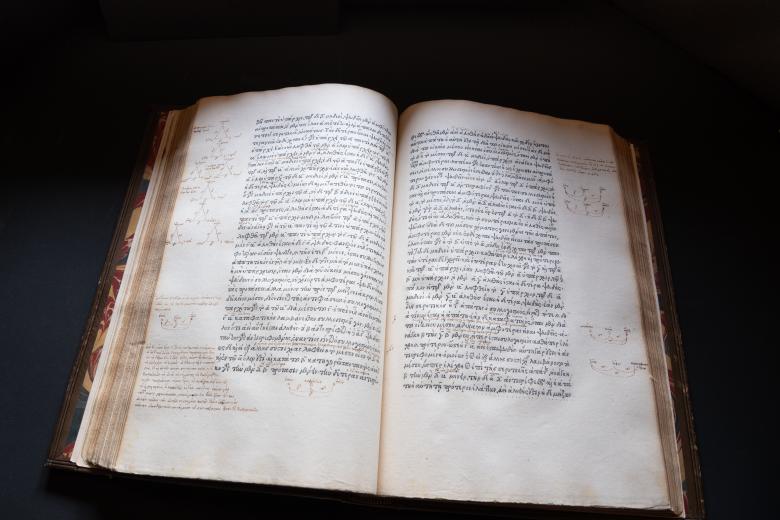 Printed text written in Greek lays flat against a dark background. In the margins, manuscript notations are visible.