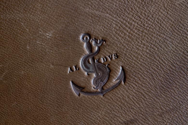 Embossed anchor, with a fish or other marine animal wrapped around it, on the binding of this book. ALDVS embossed on the cover as well.