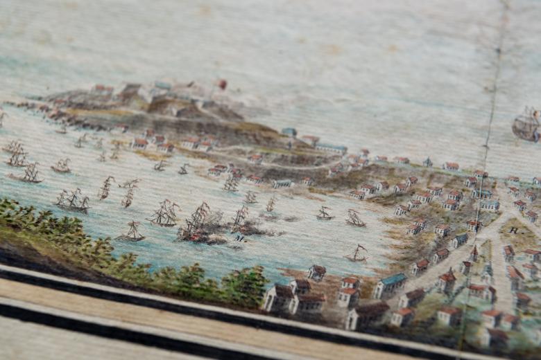 Detail of a hand colored, engraved print of Grenada shows a scene of naval warfare, as smoke engulfs a ship, and the layout of the coastal town is also visible.