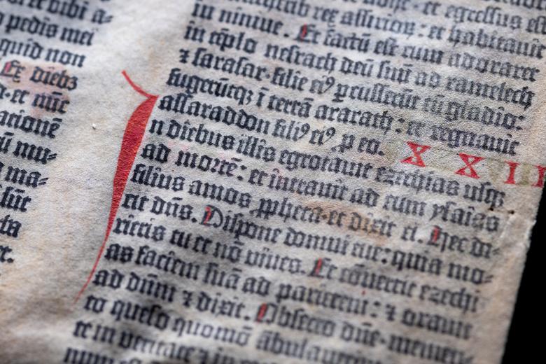 Detail of a leaf of the Gutenberg bible printed in black and red ink shows Latin text.