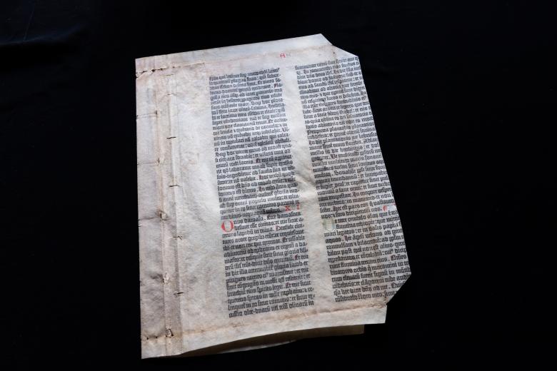 A leaf of the Gutenberg bible printed in black and red ink shows Latin text.