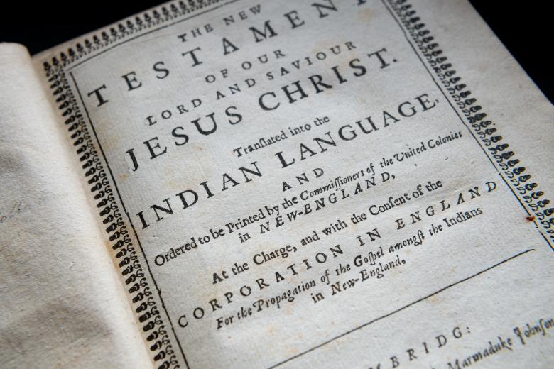 Detail of a printed book shows title page with text in Massachuset and English.