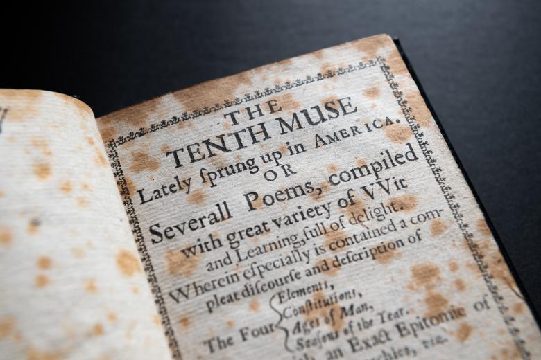 Detail of a worn title page shows printed text reading "The tenth muse lately sprung up in America. Or severall poems, compiled with great variety of wit and learning, full of delight." Decorative border also visible.