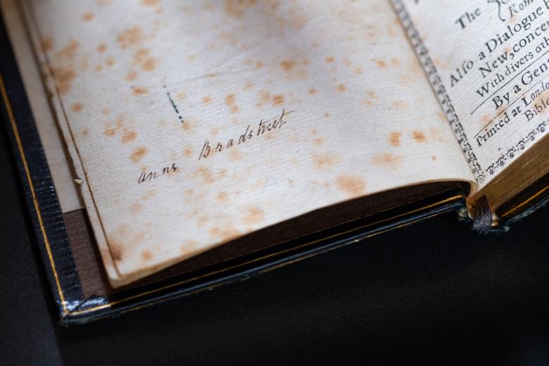 Detail of a worn page shows Anne Bradstreet's hand-written signature.