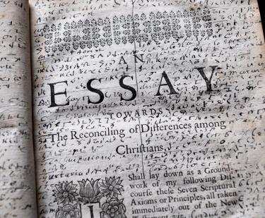 Detail of a printed book shows title page with manuscript notations throughout the blank spaces on the page.
