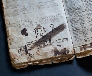 Detail of manuscript diary shows childlike drawings of a house, a person, and a ship.