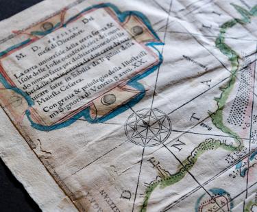 Detail of a woodcut, hand-colored map depicting North and South America. Visible details include Cuba, written as "CVBA", a compass rose, and text in Italian.