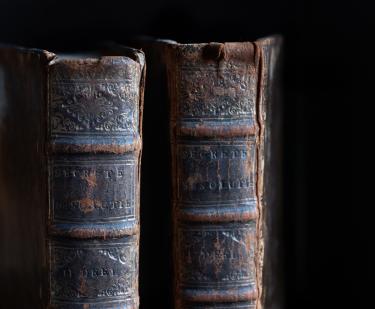 Detail of calf-bound book shows worn spine, embossed detail, and stamped title. 