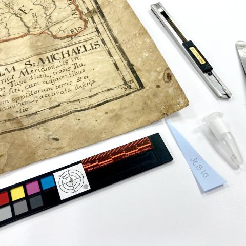 The image shows a yelowed document and conservation tools.
