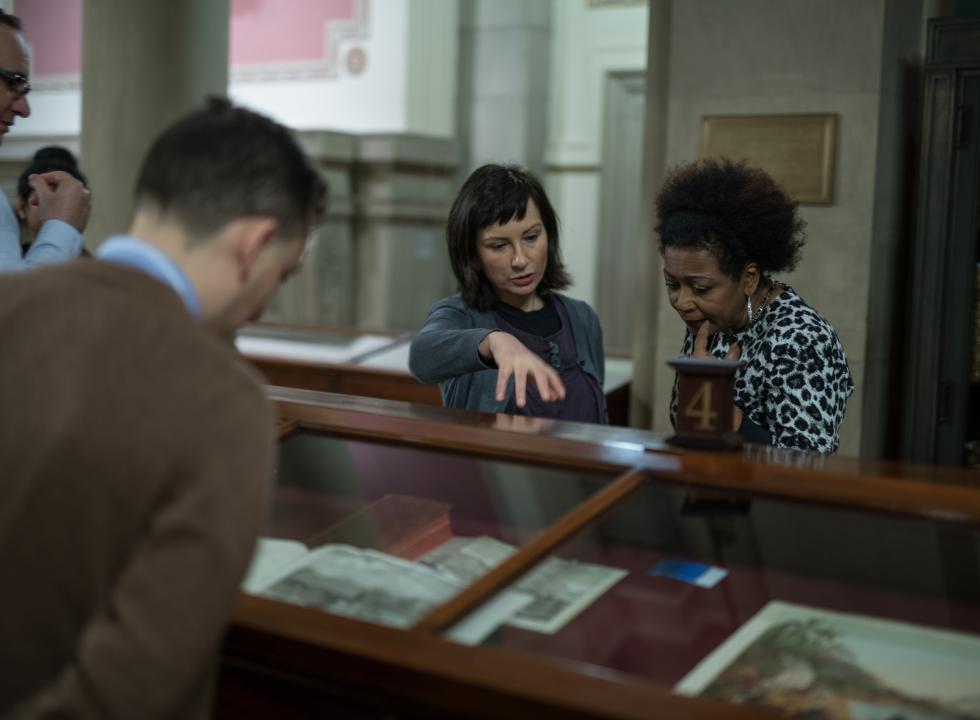 Library curator discusses materials in an exhibition with a visitor