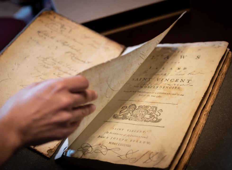 image of a hand turning the page of a rare book