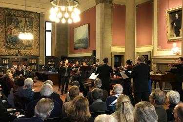 Group of people seated in the John Carter Brown Library reading room, listening to live performance by Community MusicWorks.