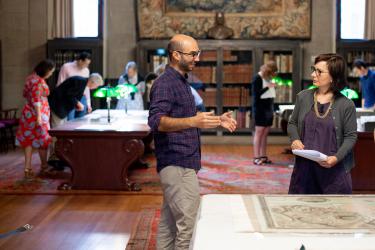 Ernesto Bassi and Bertie Mandelblatt discuss a map while researchers consult maps and books in the background