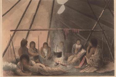 group of indigenous people sitting around a fire in an enclosed space